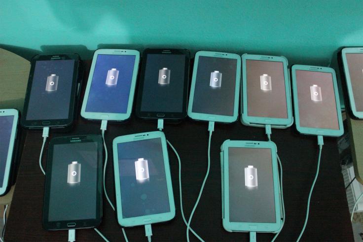 Many tablets lay charging on a table