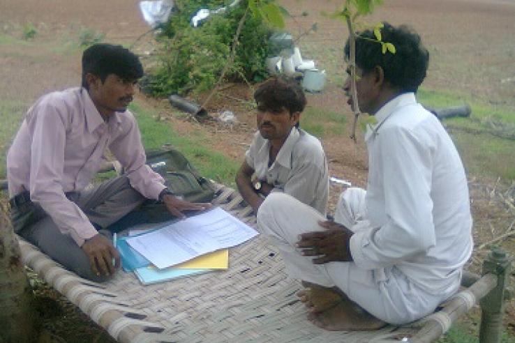 Three men talking over paperwork outdoors