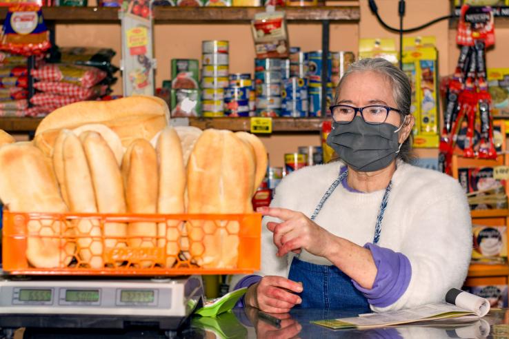 A woman wearing a mask weighs bread in a store