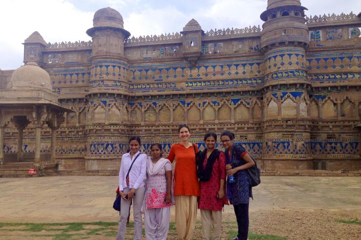 A group of five women stand in front of a historical fort.