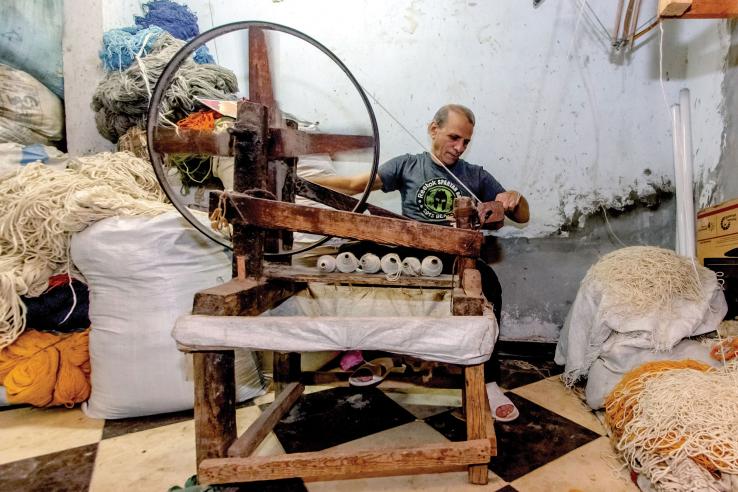 A man weaves a rug. Photo Credit: Haitham Fahmy | J-PAL