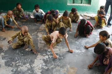 Children do arithmetic in chalk on a stone floor in India