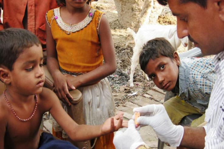 A healthcare provider measures a child's hemoglobin in India.