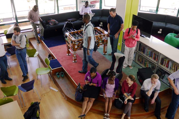 A diverse group of co-workers mingle and work together in a common work space in Nairobi, Kenya